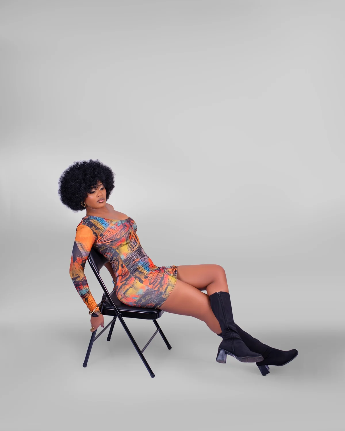 Studio portrait of a woman seated on a chair against a grey background
